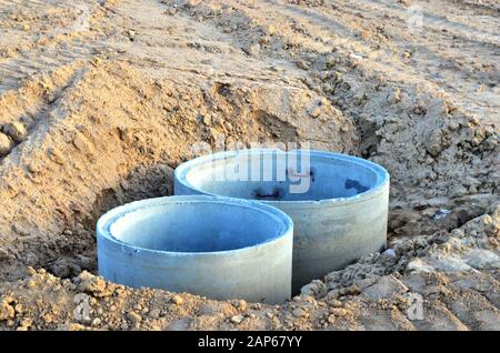 Installation von konkreten Abwasserkanal Vertiefungen im Boden auf der Baustelle. Die Verwendung von Stahlbeton Ringe für Senkgruben, Überlauf Klärgruben Stockfoto