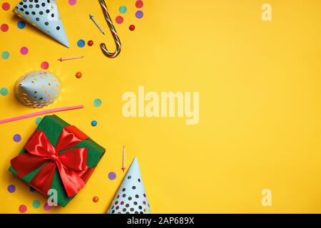 Geburtstag gelber Hintergrund mit Party-Caps-Geschenken Konfetti-Süßigkeiten-Kopierraum. Stockfoto