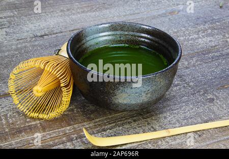 Matcha Tee Zubereitungskonzept: Nahaufnahme von isolierten Set für die Herstellung von grünem Matcha Tee: Ein Bambus Schneebesen und Schaufel, Keramik-Schüssel auf alten Holztisch Stockfoto