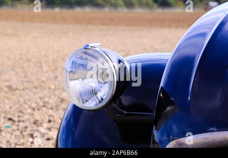 Viersen, Deutschland - 12. Oktober. 2019: Nahaufnahme des isolierten silbernen Scheinwerfers des schwarzen französischen Oldtimer-Kultwagens 2CV im ländlichen Raum Stockfoto