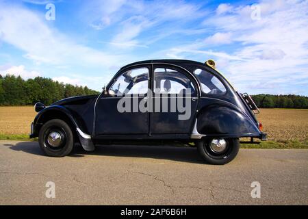 Viersen, Deutschland - 12. Oktober. 2019: Seitenansicht des schwarzen französischen Oldtimer-Kultwagens 2CV mit offenem Dach im ländlichen Raum gegen blauen Himmel Stockfoto