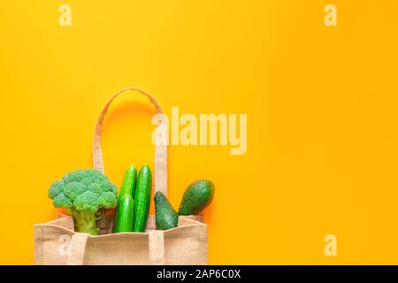 Umweltfreundliche Tragetasche aus Textil mit grünem Gemüse auf orangefarbenem Hintergrund Stockfoto