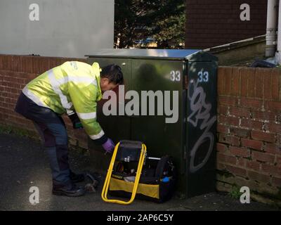 Telekommunikationsingenieur, der an einer grünen Schrankbox in einem Wohngebiet arbeitet Straße Stockfoto