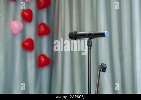 Der Vorhang des Himmels. Rote Herzballons. Weicher Fokus des Kopfmikrofons auf der Bühne des Elterntreffens von Schülern in der Sommerschule oder bei Veranstaltungen, bei denen es verschwommen ist Stockfoto