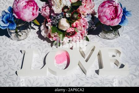 Kreative Layout mit bunten Blumen, Blättern und Wort Liebe. Liebe-Konzept. Stockfoto