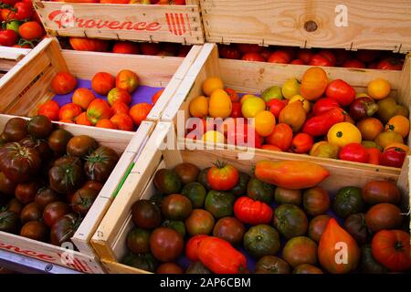 Verschiedene Arten von roten, gelben und schwarzen provenzalischen französischen reifen frischen Tomaten in Holzobstkästen auf dem Bauernmarkt - Provence, Frankreich Stockfoto