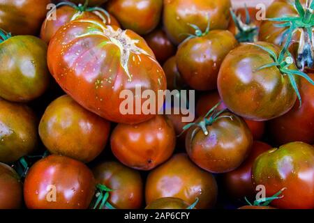 Vollformataufnahme von glänzend reifen schwarzen und roten Tomaten auf dem französischen Markt - Provence, Frankreich Stockfoto
