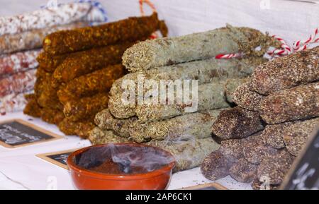 Nahaufnahme von Pfählen französischer geräucherter Salamiwürste, gewürzt mit Kräutern aus der Provence auf dem Bauernmarkt - St. Tropez, Frankreich Stockfoto