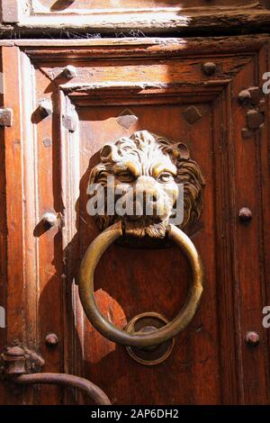 Nahaufnahme von antiken Metall-Tür-Stockern in Form von Löwenkopf mit Ring am Eingang aus altem Holz mit Kerben in hellem natürlichem Sonnenlicht - Provence, Stockfoto