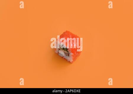 Kalifornische Maki Sushi rollen mit Kaviar und Maago auf orangefarbenem Hintergrund in Nahaufnahme. Minimalismus Draufsicht flach lag mit japanischem Essen Stockfoto