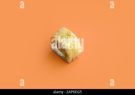 Tori Katsu Sushi Roll Maki mit verarbeitetem Käse auf orangefarbenem Hintergrund. Minimalismus Draufsicht flach lag mit japanischem Essen Stockfoto