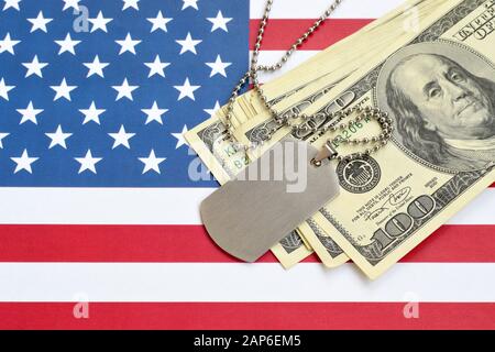 Armee-Identifikationsmedaillons und Dollarscheine auf der Flagge der Vereinigten Staaten. Militärrente, Gehalt in der Armee oder Militärversicherung, Lohnunternehmer rekrutieren Stockfoto