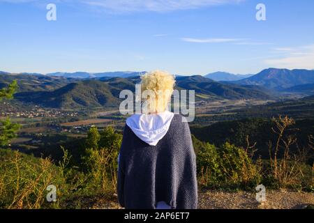 Blick auf eine isolierte Frau mit blonden lockigen Haaren auf dem Plateau, Blick auf ein endloses Tal mit Bergkette - Grand Canyon du Verdon, Frankreich Stockfoto