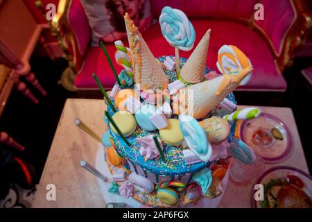 Dekoration für Kuchen und Bekleierung. Farbenfroher Kuchen aus Waffelkegel für Eis im Sortiment, mit Süßwaren auf weißem Holz bestreut Stockfoto