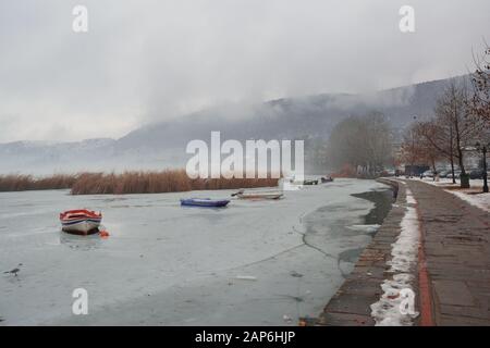 Fußgängerzone am Ufer des zugefrorenen Sees Orestiada in Kastoria, Griechenland an einem trübem Tag Stockfoto