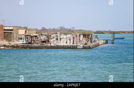 Fadiouth, Senegal, AFRIKA - 26. April 2019: Unidentifizierte senegalesische Jungen vor den zerstörten Häusern im Dorf Fadiouth gibt es wenig Stockfoto