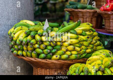 Rohbananen und reife Bananen, die auf den Verkauf auf dem Obstmarkt warten. Hintergrundtextur von grünen Bananen und gelben Bananen. Stockfoto
