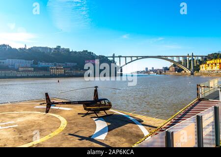 Porto Malerische Aussicht auf einen Helitours-Hubschrauber mit Arrabida-Brücke an einem sonnigen blauen Himmelstag im Winter Stockfoto