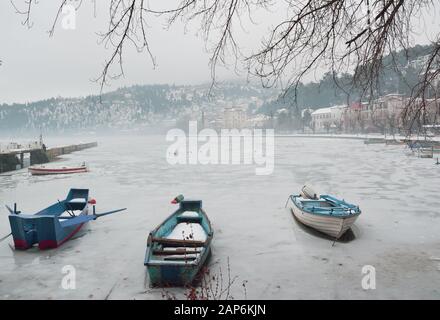 Boote in einem kleinen Dock, gefangen im gefrorenen See von Orestiada in Kastoria, Griechenland Stockfoto