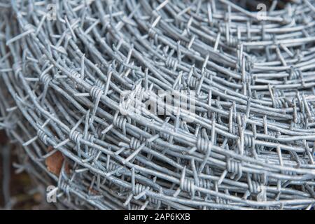 Auf einer Pfahlrolle aus glänzendem, neuem Stacheldraht zum Zaunfechten schließen. Durchsetzung von Sicherheitsvorschriften. Straftat des Gefängnis-Strafvollzugs gesperrt. Stockfoto