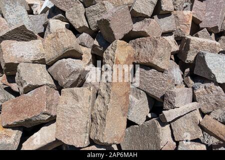Raue, zerbrochene Pflastersteine aus Granit in einem Haufen Stockfoto