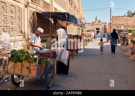 Tunisia, Oktober 10/2019 Tunesischer traditioneller Markt, Frau in traditioneller Kleidung kauft Gemüse von einem Mann mit Holzkarren, direkt im Background Stockfoto