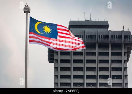 Große malaysische Flagge, die in de Wind weht und ein großes Gebäude im Hintergrund, Kuala Lumpur Stockfoto