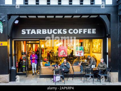 Leute, die außerhalb des Starbucks Coffeeshops in Chester England sitzen Stockfoto