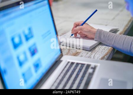 Nahaufnahme der Handfrau, die mit einem Stift an einem Dokument arbeitet, in der Nähe ihres Computer-Laptops-pcs in ihrem Büro zu Hause an ihrem Arbeitsplatz, Desktop-Geschäft Stockfoto