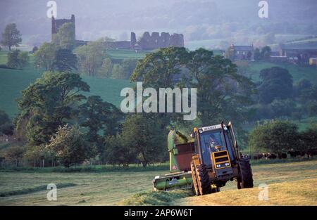 Landwirt silaging eine Wiese mit einem gezogenen Chopper, mit Brough Schloss im Hintergrund. Cumbria, Großbritannien. Stockfoto