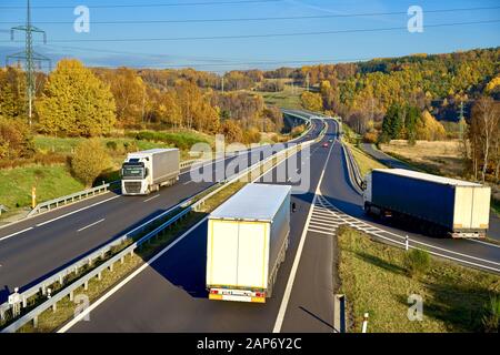 Drei fahren auf einer Landstraße in der bewaldeten Herbstlandschaft vorbei. Autos und elektronisches Mauttor in der Ferne. Ansicht von oben. Stockfoto