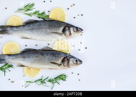 Roher Meeresbass mit Gewürzen und Kräutern auf einem weißen Schiefertisch. Frischer Meeresbass. Draufsicht mit Kopierbereich. Stockfoto