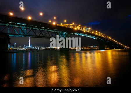 Blick über den Waitemata Harbour in der Innenstadt von Auckland, nachts von der North Shore mit der Harbour Bridge im Vordergrund. Neuseeland. Stockfoto