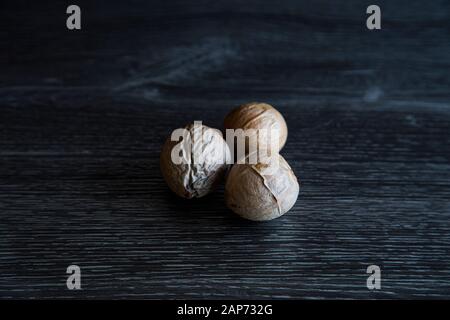 Low Key Bild von 3 verschiedenen Avocadosamen in einer Gruppe. Hartes Licht zeigt die Venen und die trockene Hautschicht der Pips. Es sind viele Details zu sehen. Stockfoto