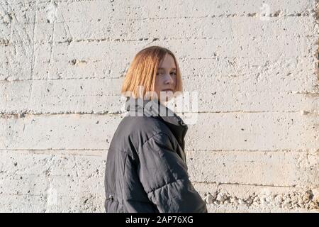 Wunderschönes Mädchen im Teenager-Alter mit kurzen Haaren, die in der Nähe der Graffitiwand pos Urbane Natur, Teenager-Lifestyle Stockfoto