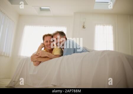 Porträt eines glücklichen, homosexuellen Paares, das zusammen auf einem Bett liegt. Stockfoto