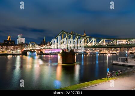 Die beleuchtete Fußgängerbrücke Eiserner Steg, die nachts den Main in Frankfurt überquert Stockfoto