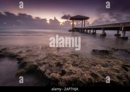 Pavillon am Pier mit nebligen Wellen, die auf felsigem Ufer, Grand Cayman Island, abstürzen Stockfoto