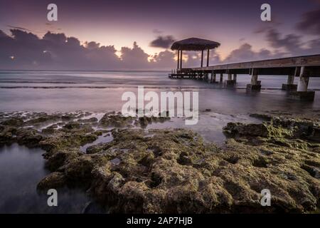 Pavillon am Pier mit nebligen Wellen, die auf felsigem Ufer, Grand Cayman Island, abstürzen Stockfoto