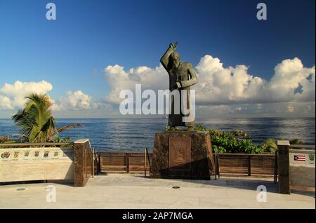 Eine Statue von Johannes dem Täufer mit einer schönen Kulisse eines trüben Atlantiks blickt auf die Plaza San Juan Bautista im Alten San Juan, Puerto Rico Stockfoto