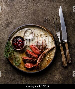 Gegrillte, geschnittene Wildlippen und Beerensauce auf dunklem Hintergrund Stockfoto