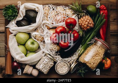 Lebensmitteleinkäufe ohne Verschwendung. Obst und Gemüse in Baumwolltüten, Pasta, Getreide und Hülsenfrüchte in Glasgefäßen, Kräutern und Gewürzen auf Holzgrund. Gesundheit Stockfoto