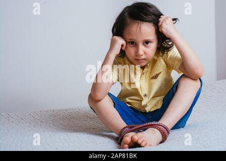 Kleine oy mit Füßen, die mit Seil in emotionalem Stress verbunden sind Stockfoto