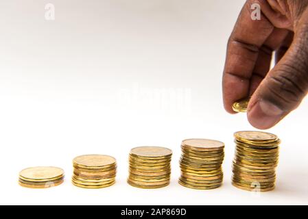 Kanadische Dollar-Münzen in fünf aufsteigende Stapel auf weißem Hintergrund getackelt. Man kann sehen, wie man eine Münze nimmt oder dem Stapel hinzufügt. Stockfoto