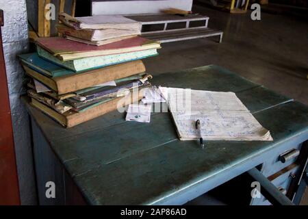 Ein alter Schreibtisch, gestapelt mit Ledgern und handschriftlichen Protokollnotizen auf dem Teestand Puttabong. In Darjeeling, Westbengalen, Indien. Stockfoto