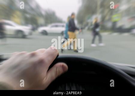 Notfall. Blick aus dem Auto, Hand eines Mannes am Lenkrad des Autos beim Bremsen, vor einem Fußgängerübergang und Fußgänger-Kreuzung Stockfoto