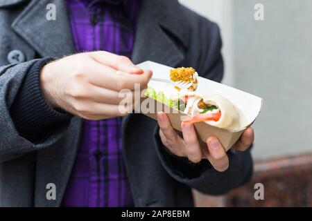 Der Mann hält Falafel-Sandwich in Papiertüte. Gesundes Straßennahrungskonzept, orientalische Küche Stockfoto