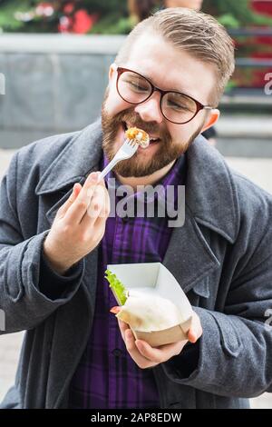 Der Mann hält Falafel-Sandwich in Papiertüte. Gesundes Straßennahrungskonzept, orientalische Küche Stockfoto