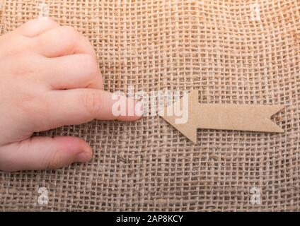 Pfeilschild aus braunem Papier gegen einen f'iger auf Leinwand geschnitten Stockfoto