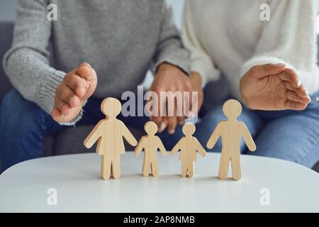 In den Händen einer Frau befindet sich eine Familie von Holzfiguren. Familienplanung Schutzkonzept Stockfoto